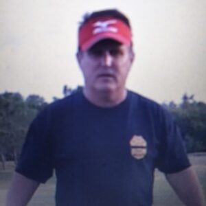 Man wearing a red cap and dark shirt outdoors.