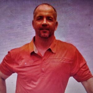 Man in a red polo shirt posing against a plain background.