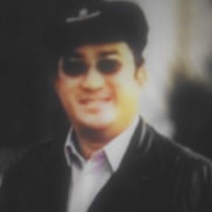 A person wearing sunglasses and a hat, smiling at the camera.