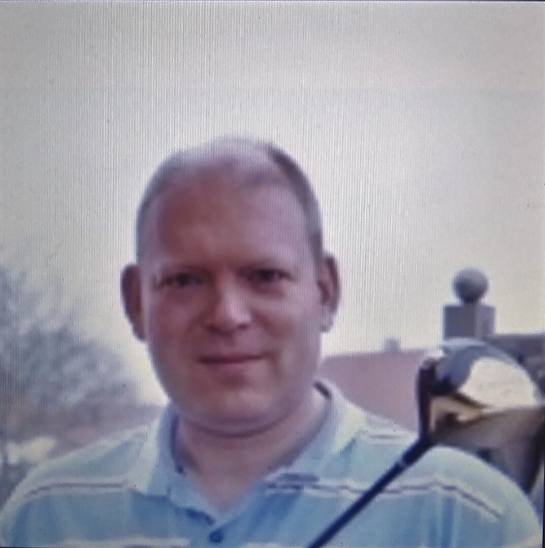 Smiling man outdoors wearing a striped polo shirt.