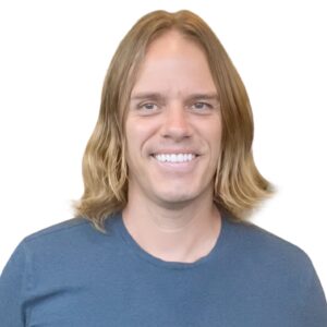 Smiling man with long blond hair wearing a blue shirt.