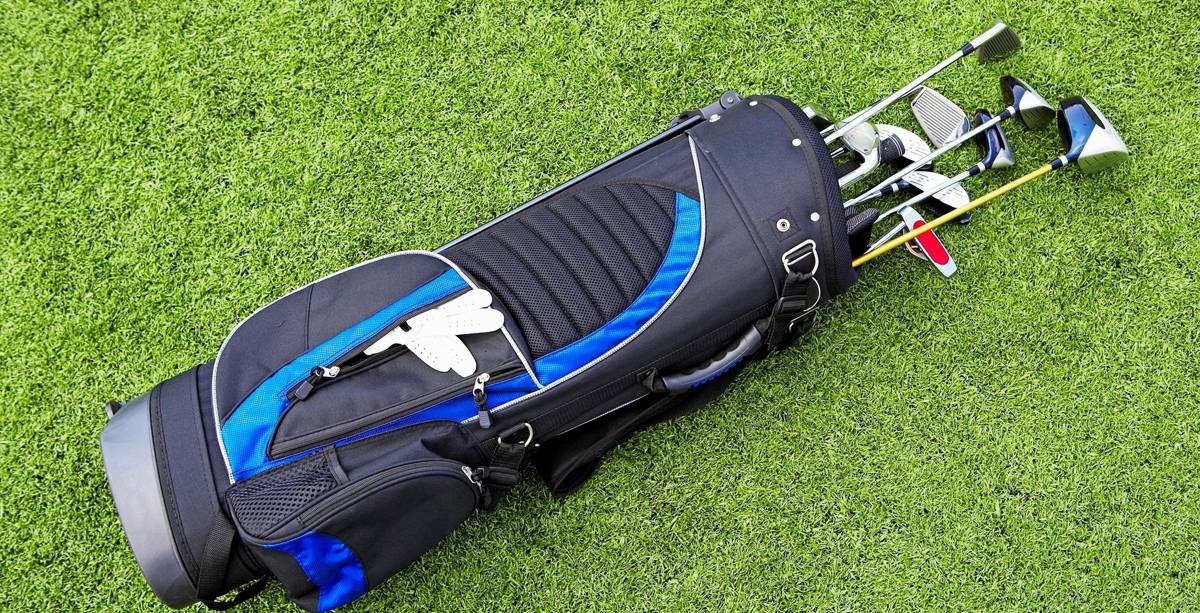 Golf bag with clubs on green grass.