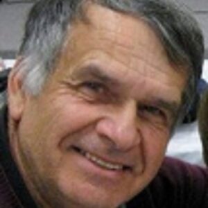 Smiling elderly man with gray hair and warm eyes.