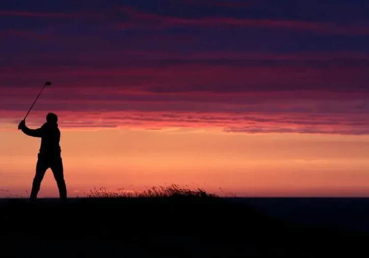 Silhouette of a person standing against a vibrant sunset sky.